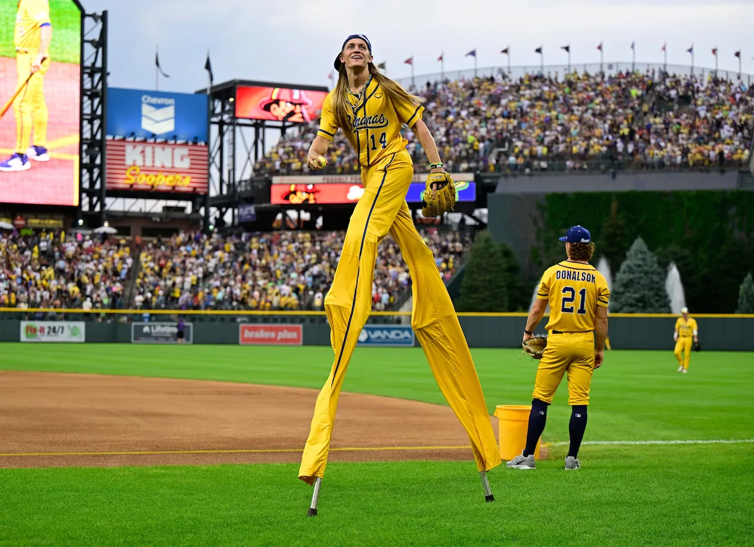 Savannah Bananas player Dakota Albritton performs on stilts in front of a packed crowd at Coors Field