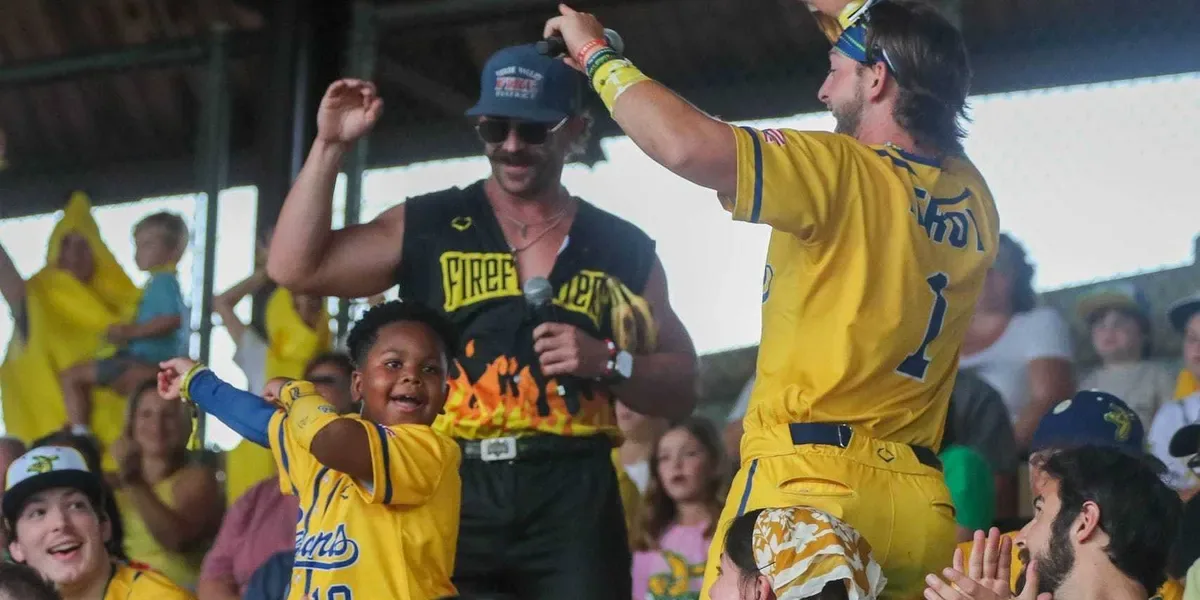 Banana Ball players celebrate with a young fan on the field
